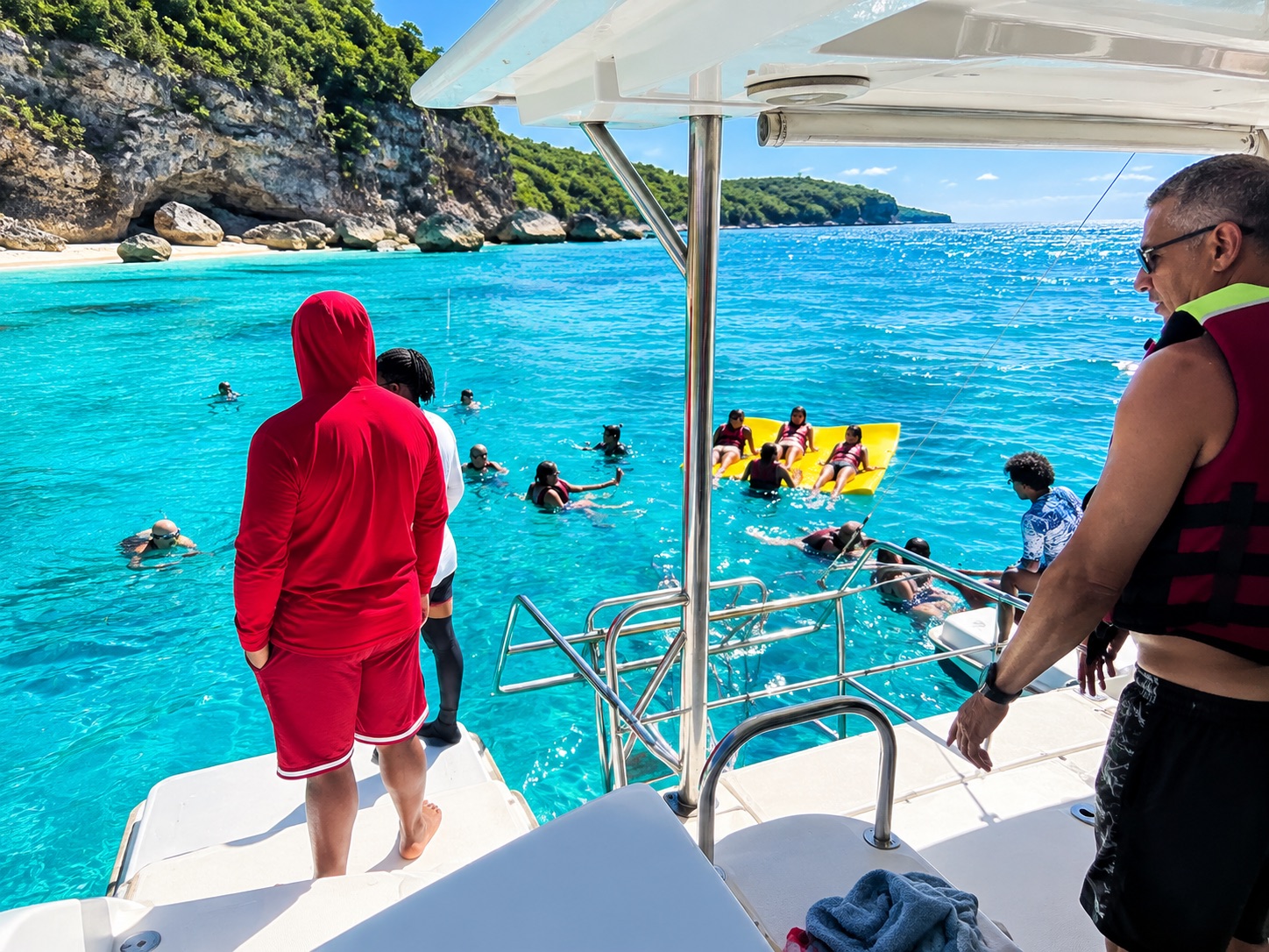 Guests wearing life jackets swimming beside the catamaran